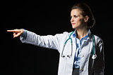 Doctor woman pointing on copy space isolated on black