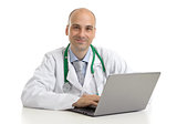 cheerful doctor sitting at the desk working on laptop