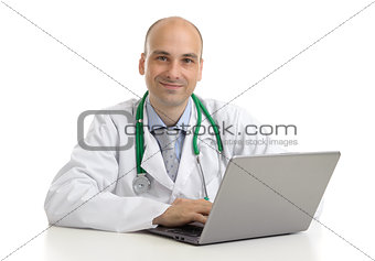 cheerful doctor sitting at the desk working on laptop