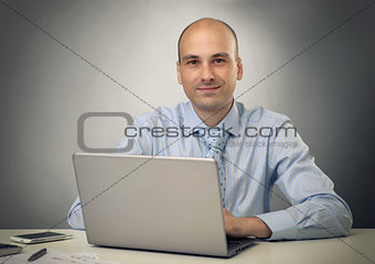 Handsome young business man in office with laptop