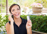 Young Adult Woman Holding Cell Phone and Credit Card Outside