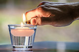Hand with a lighter lighting a candle