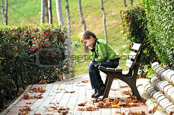 sad boy sitting alone on a bench in a way