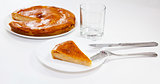 Piece of onion pie with fork and knife and glass