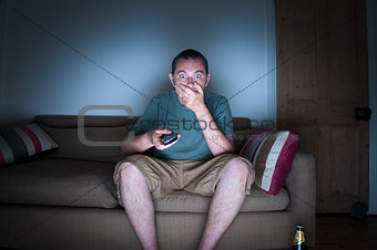 man covering mouth watching tv