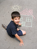Child drawing sun and house on asphal