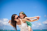 Young beautiful mother and her adorable little daughter at tropical beach