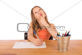 Child sitting at a table trying to make a drawing