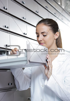 Young female pharmacist reaching for medicine