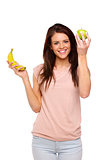 Brunette woman holding up an apple and banana