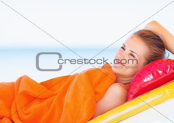 Happy young woman laying on chaise-longue