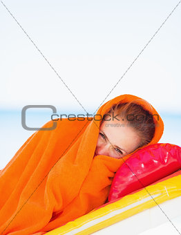 Young woman wrapped in towel laying on sunbed