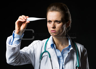 Doctor woman looking on thermometer isolated on black