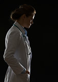 Silhouette of thoughtful doctor woman isolated on black