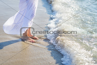 Closeup on leg of young woman standing on sea shore