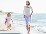 Happy mother and baby running on sea shore