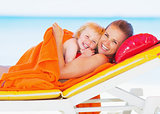 Portrait of smiling mother and baby laying on sunbed