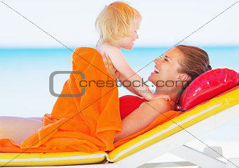 Happy mother and baby laying on sunbed