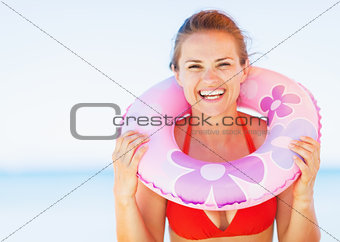 Portrait of smiling young woman on beach with swim ring
