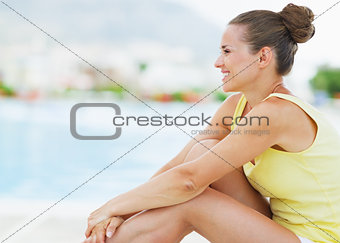 Happy young woman sitting on sunbed