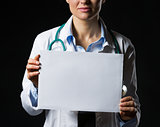 Closeup on doctor woman showing blank paper sheet isolated on bl
