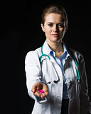 Doctor woman showing pills isolated on black