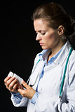 Doctor woman looking on medicine bottle isolated on black