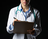 Closeup on doctor woman writing in clipboard isolated on black