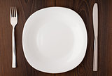 White empty plate, knife and fork served on table