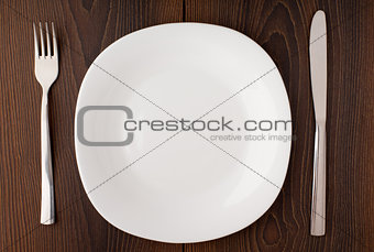 White empty plate, knife and fork served on table
