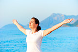 Woman with arms outstretched enjoying the sun by the sea