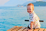 happy little boy sitting on a pier