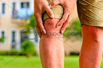 man holding hands sore knee