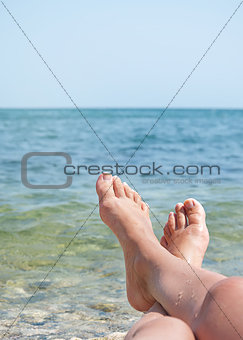 female legs over sea waves and sky