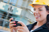 Female Contractor Wearing Hard Hat on Site Texting with Phone