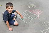 Child drawing sun and house on asphal