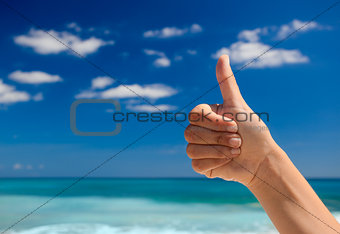 Thumbs up against a blue sky