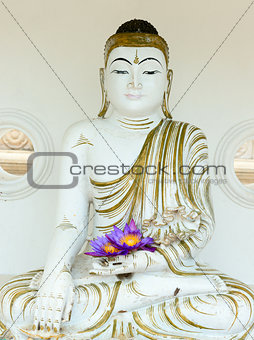 Buddha image statue with fresh flowers in hands