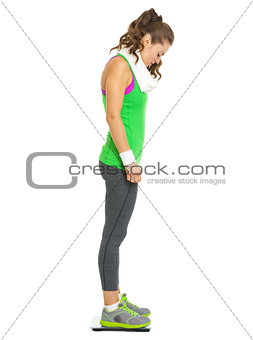 Full length portrait of fitness young woman standing on scales