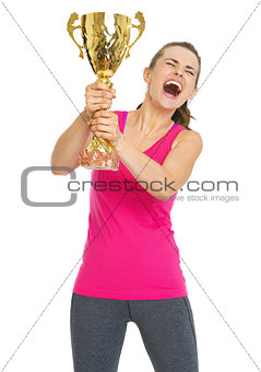 Happy fitness young woman holding gold trophy cup