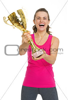 Smiling fitness young woman showing gold trophy cup