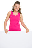Smiling fitness young woman showing blank billboard
