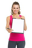 Smiling fitness trainer giving clipboard for sign