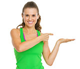 Smiling fitness young woman presenting something on empty palm