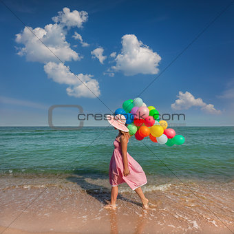 Young woman walking on the beach with colored balloons / Relax