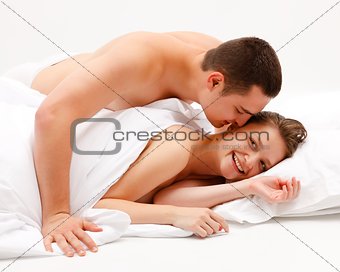 Man leaning over smiling woman in bed