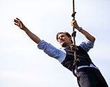 Determined businessman climbing a rope, reaching