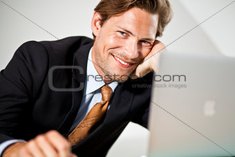Smiling Caucasian businessman using laptop