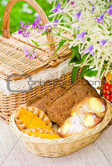 Buns in a wicker basket and a bouquet of field flowers  close-up