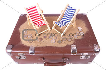 Vintage suitcase with euro coins lie in front of toy beach chair